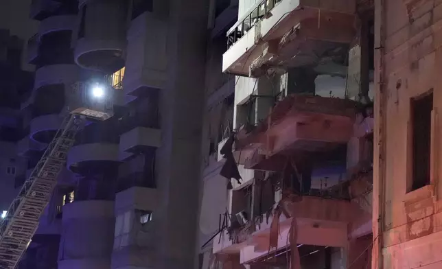 Rescue workers standing on a crane check a destroyed building hit by an Israeli airstrike in central Beirut, Lebanon, Thursday, Oct. 10, 2024. (AP Photo/Hassan Ammar)