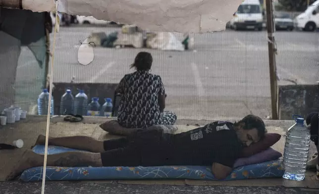 A family fleeing the Israeli airstrikes in Dahiyeh, sits in Martyrs' square in Beirut, Lebanon, Monday, Oct. 14, 2024. (AP Photo/Bilal Hussein)