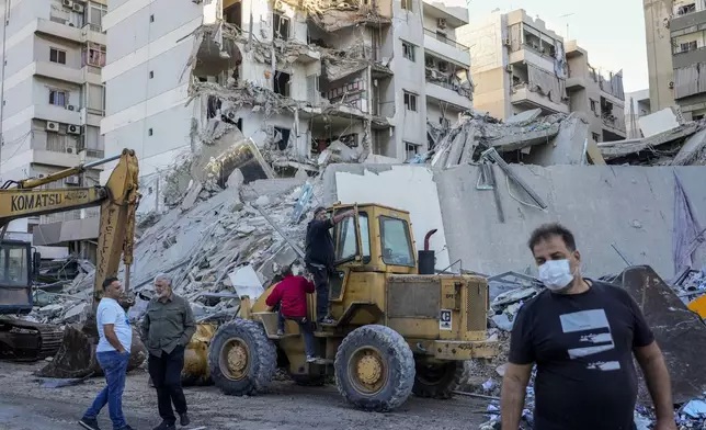 Rescue workers use a bulldozer to remove rubble of destroyed buildings at the site of an Israeli airstrike on Sunday night that hit several branches of the Hezbollah-run al-Qard al-Hassan in Beirut's southern suburb, Lebanon, Monday, Oct. 21, 2024. (AP Photo/Hassan Ammar)