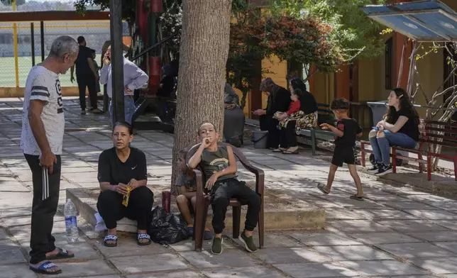 Displaced people sit at a vocational training center run by the U.N. agency for Palestinian refugees, or UNRWA, in the town of Sebline, south of Beirut, Lebanon, Friday, Oct. 4, 2024, after fleeing the Israeli airstrikes in the south. (AP Photo/Bilal Hussein)