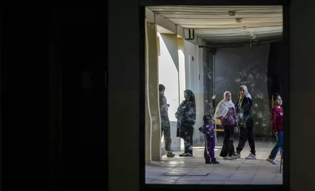 Displaced children, who fled Baalbek city and the nearby towns of Douris and Ain Bourday with their families amid the ongoing Hezbollah-Israel war, are reflected in a mirror inside a school being used as a shelter, in Deir Al-Ahmar, east Lebanon, Thursday, Oct. 31, 2024. (AP Photo/Hassan Ammar)