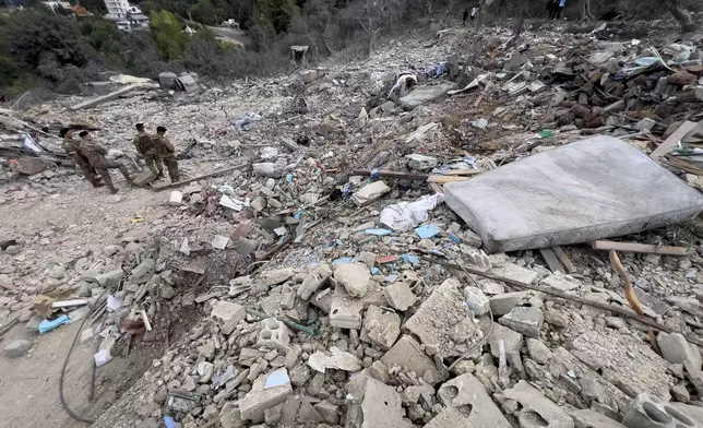 Lebanese army soldiers stand on the rubble of a destroyed building at the site of Monday's Israeli airstrike in the village of Aito, north Lebanon, Tuesday, Oct. 15, 2024. (AP Photo/Hussein Malla)