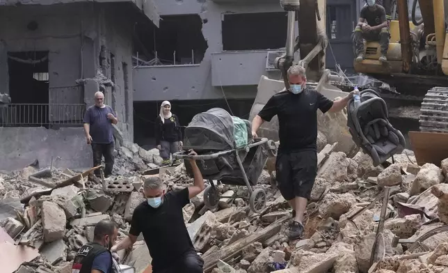 Residents of a building damaged in an Israeli airstrike return to collect their family's belongings at the site of Thursday's Israeli airstrike in Beirut, Lebanon, Saturday, Oct. 12, 2024. (AP Photo/Hassan Ammar)