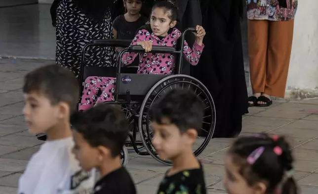 Zahraa on a wheel chair looks on as volunteers of the Russian Cultural Center entertain displaced children at a school in Beirut, Lebanon, Thursday, Oct. 3, 2024, after fleeing the Israeli airstrikes in the south. (AP Photo/Bilal Hussein)