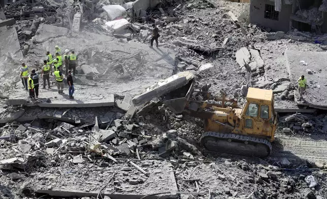 Rescue workers use a bulldozer to remove rubble of destroyed buildings, as they search for victims at the site that was hit by Israeli airstrikes in Qana village, south Lebanon, Wednesday, Oct. 16, 2024. (AP Photo/Mohammed Zaatari)