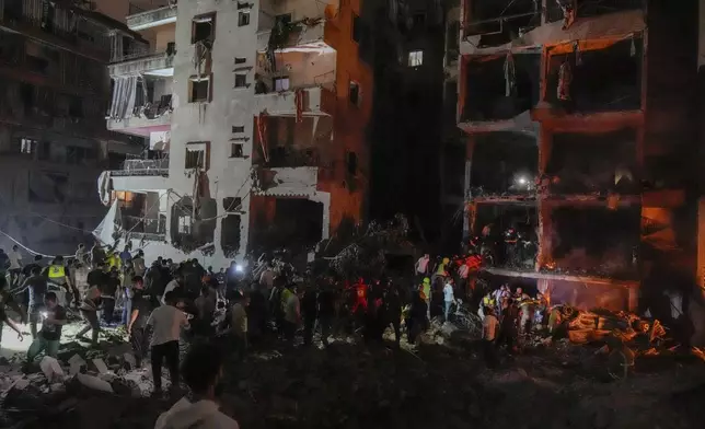 People gather in front of destroyed buildings hit by an Israeli airstrike in central Beirut, Lebanon, Thursday, Oct. 10, 2024. (AP Photo/Bilal Hussein)