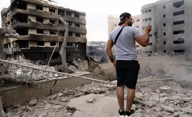 A man takes pictures by his mobile phone of destroyed buildings hit by Israeli airstrikes in Dahiyeh, Beirut, Lebanon, Monday, Oct. 7, 2024. (AP Photo/Hussein Malla)