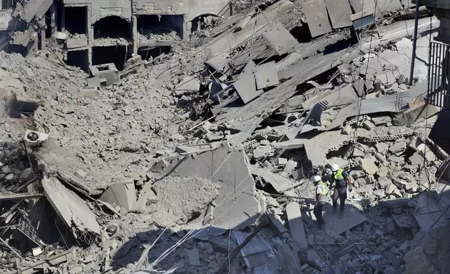 Hezbollah rescue workers search for victims amidst the rubble of destroyed buildings at a commercial street that was hit Saturday night by Israeli airstrikes, in Nabatiyeh town, south Lebanon, Sunday, Oct. 13, 2024. (AP Photo/Mohammed Zaatari)