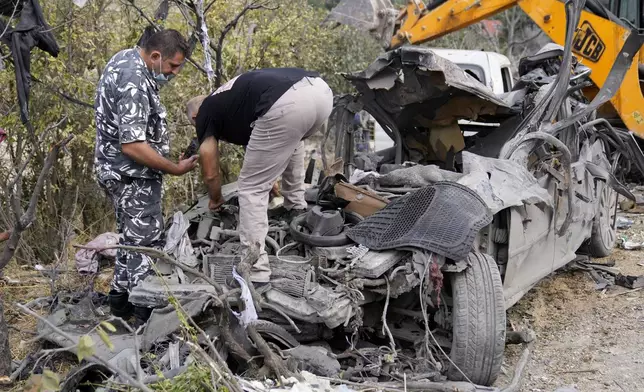 Lebanese policemen check a destroyed car at the site of Monday's Israeli airstrike in Aito village, north Lebanon, Tuesday, Oct. 15, 2024. (AP Photo/Hussein Malla)