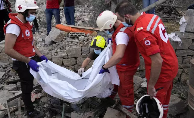 Lebanese Red Cross volunteers remove the remains of killed people from the rubble of a destroyed building at the site of Monday's Israeli airstrike in Aito village, north Lebanon, Tuesday, Oct. 15, 2024. (AP Photo/Hussein Malla)