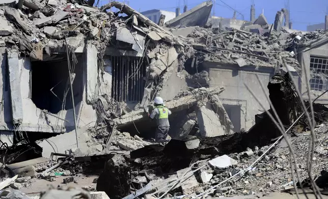 A Hezbollah rescue worker searches for victims amidst the rubble of destroyed buildings at a commercial street that was hit Saturday night by Israeli airstrikes, in Nabatiyeh town, south Lebanon, Sunday, Oct. 13, 2024. (AP Photo/Mohammed Zaatari)