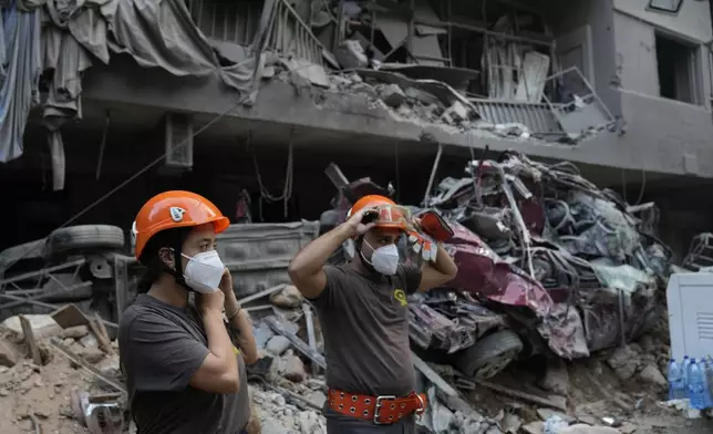 Rescue workers stand in front of destroyed buildings, as they prepare to start search for victims at the site of Thursday's Israeli airstrike, in Beirut, Lebanon, Friday, Oct. 11, 2024. (AP Photo/Hussein Malla)