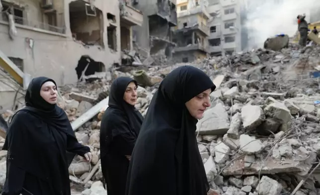 Lebanese women pass destroyed buildings at the site of Thursday's Israeli airstrike, in Beirut, Lebanon, Friday, Oct. 11, 2024. (AP Photo/Hussein Malla)