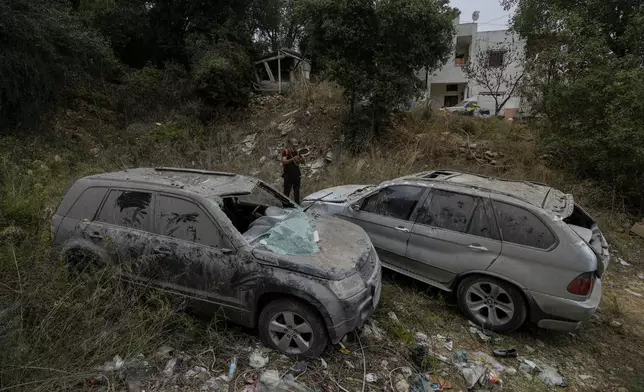 A man stand next to damaged cars near a building that was hit by Israeli airstrikes in the village of Qmatiyeh, southeast Beirut, Lebanon, Monday, Oct. 7, 2024. (AP Photo/Bilal Hussein)