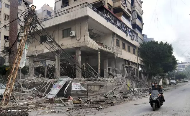 Lebanese men ride a scooter past a damaged building hit by an Israeli airstrike in Dahiyeh, Beirut, Lebanon, Monday, Oct. 7, 2024. (AP Photo/Hussein Malla)