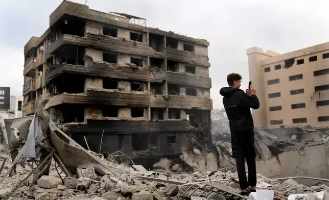 A man takes pictures by his mobile phone of destroyed buildings hit by Israeli airstrikes in Dahiyeh, Beirut, Lebanon, Monday, Oct. 7, 2024. (AP Photo/Hussein Malla)