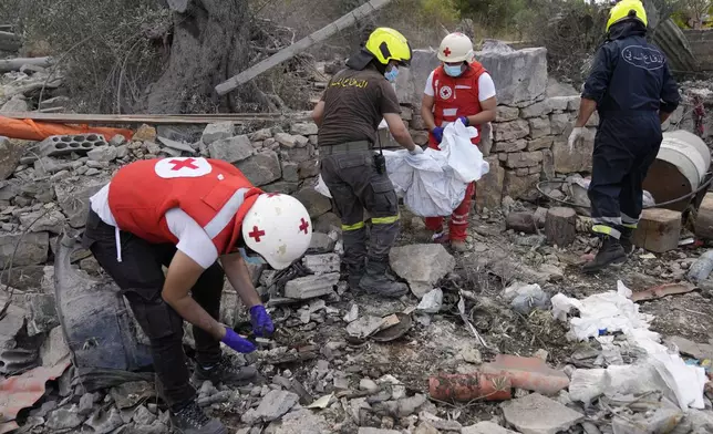 Lebanese Red Cross volunteers and Civil Defence workers remove the remains of killed people from the rubble of a destroyed building at the site of Monday's Israeli airstrike in Aito village, north Lebanon, Tuesday, Oct. 15, 2024. (AP Photo/Hussein Malla)