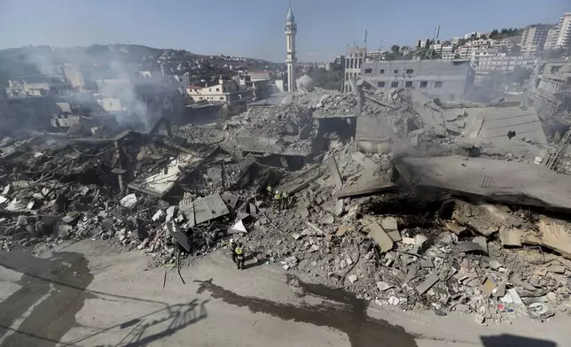 Hezbollah rescue workers search for victims amid the rubble of destroyed buildings at commercial street that was hit Saturday night by Israeli airstrikes, in Nabatiyeh town, south Lebanon, Sunday, Oct. 13, 2024. (AP Photo/Mohammed Zaatari)