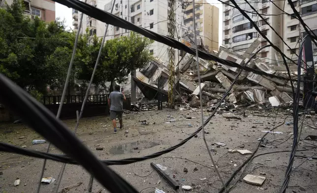 A man checks the damaged buildings at the site of an Israeli airstrike in Beirut's southern suburb, Lebanon, Tuesday, Oct. 1, 2024. (AP Photo/Hassan Ammar)