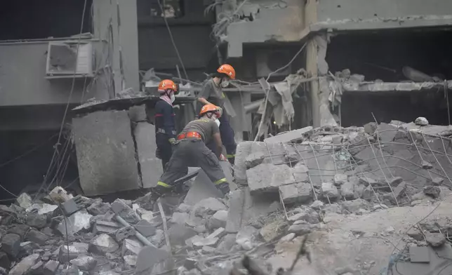 Rescue workers clear the rubble of destroyed buildings as they search for victims at the site of Thursday's Israeli airstrike, in Beirut, Lebanon, Friday, Oct. 11, 2024. (AP Photo/Hussein Malla)