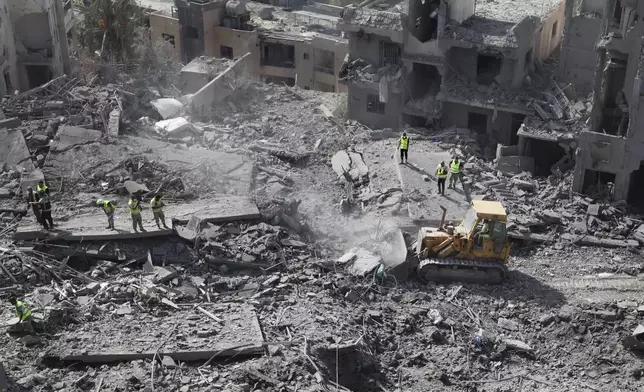 Rescue workers use a bulldozer to remove rubble of destroyed buildings at the site that was hit by Israeli airstrikes in Qana village, south Lebanon, Wednesday, Oct. 16, 2024. (AP Photo/Mohammed Zaatari)