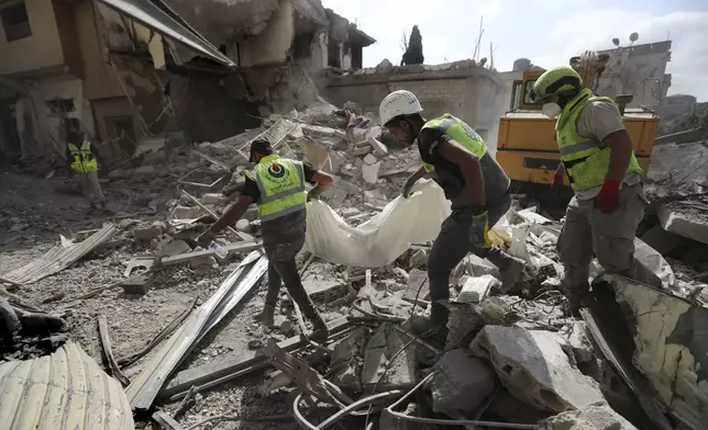 Rescue workers carry remains of killed people at the site that was hit by Israeli airstrikes in Qana village, south Lebanon, Wednesday, Oct. 16, 2024. (AP Photo/Mohammed Zaatari)