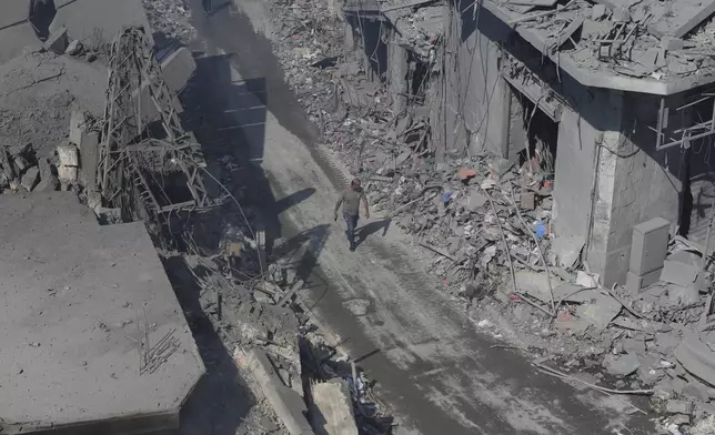 A man walks amid destroyed buildings at a commercial street that was hit Saturday night by Israeli airstrikes, in Nabatiyeh town, south Lebanon, Sunday, Oct. 13, 2024. (AP Photo/Mohammed Zaatari)