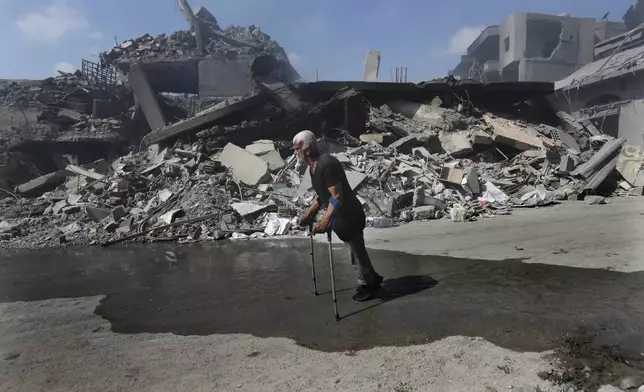 A man walks in front of destroyed buildings on a commercial street that was hit Saturday night by Israeli airstrikes, in Nabatiyeh town, south Lebanon, Sunday, Oct. 13, 2024. (AP Photo/Mohammed Zaatari)