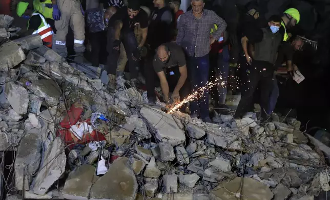 Rescue workers search for victims at a destroyed building hit in an Israeli airstrike, in the southern port city of Sidon, Lebanon, Tuesday, Oct. 29, 2024. (AP Photo/Mohammed Zaatari)
