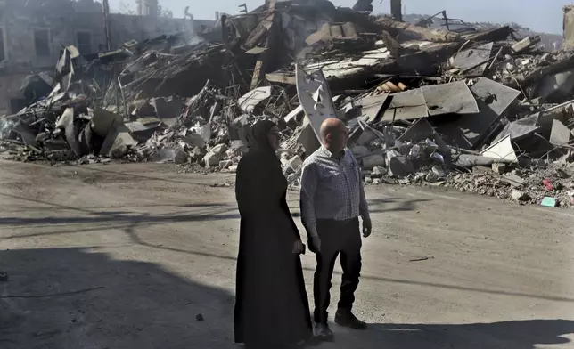 Lebanese citizens watch the destroyed buildings at commercial street that was hit Saturday night by Israeli airstrikes, in Nabatiyeh town, south Lebanon, Sunday, Oct. 13, 2024. (AP Photo/Mohammed Zaatari)