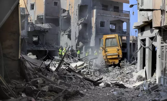 Rescue workers use a bulldozer to remove rubble of destroyed buildings, as they search for victims at the site that was hit by Israeli airstrikes in Qana village, south Lebanon, Wednesday, Oct. 16, 2024. (AP Photo/Mohammed Zaatari)