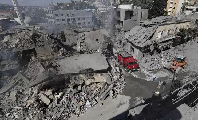 Hezbollah rescue workers use a bulldozer to remove the rubble of destroyed buildings on a commercial street that was hit Saturday night by Israeli airstrikes, in Nabatiyeh town, south Lebanon, Sunday, Oct. 13, 2024. (AP Photo/Mohammed Zaatari)