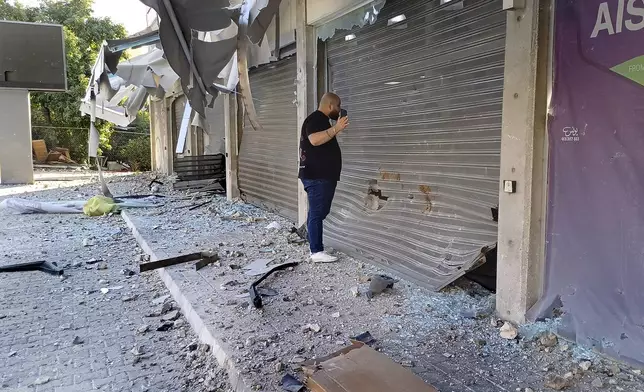 A man checks damaged shops at the site of an Israeli airstrike that hit a building, in the southern port city of Sidon, Lebanon, Sunday, Oct. 27, 2024. (AP Photo/Mohammed Zaatari)