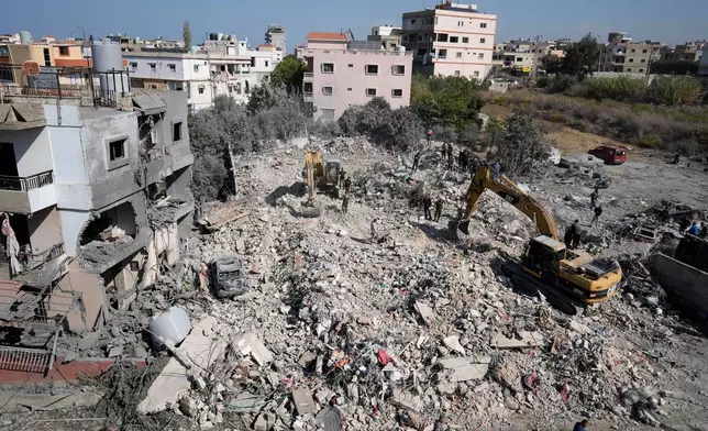 Rescue workers use excavators to remove the rubble of a destroyed building that was hit Tuesday night in an Israeli airstrike, as they search for victims in Sarafand, south Lebanon, Wednesday, Oct. 30, 2024. (AP Photo/Bilal Hussein)