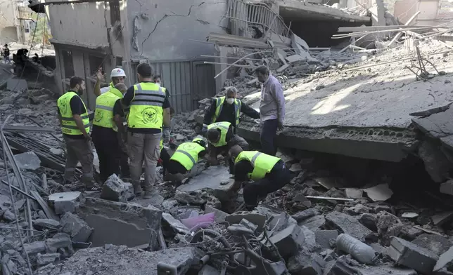 Rescue workers remove rubble, as they search for victims at the site that was hit by Israeli airstrikes in Qana village, south Lebanon, Wednesday, Oct. 16, 2024. (AP Photo/Mohammed Zaatari)