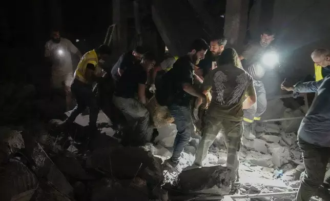 People carry a body at the scene of destroyed buildings hit by an Israeli airstrike in central Beirut, Lebanon, Thursday, Oct. 10, 2024. (AP Photo/Bilal Hussein)