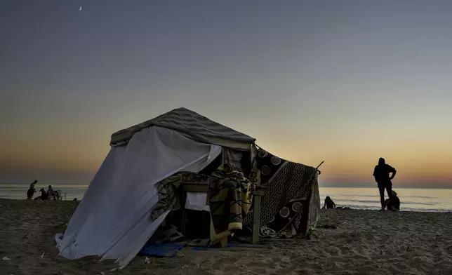 A displaced family stand next to their tent as a temporary shelter at Ramlet al-Baida public beach, after fleeing the Israeli airstrikes in the south, in Beirut, Lebanon, Tuesday, Oct. 8, 2024. (AP Photo/Bilal Hussein)