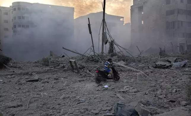 A man rides his scooter through debris of destroyed buildings hit by Israeli airstrikes in Dahiyeh, Beirut, Lebanon, Sunday, Oct. 6, 2024. (AP Photo/Hussein Malla)