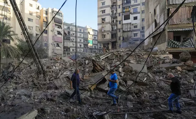 People check damaged buildings at the site of an Israeli airstrike in Dahiyeh, Beirut, Lebanon, Friday, Oct. 4, 2024. (AP Photo/Hassan Ammar)