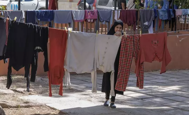 Turkeya Mohammed hangs her family's laundry at a vocational training center run by the U.N. agency for Palestinian refugees, or UNRWA, in the southern town of Sebline, south of Beirut, Lebanon, Friday, Oct. 4, 2024, after fleeing the Israeli airstrikes in the south. (AP Photo/Bilal Hussein)