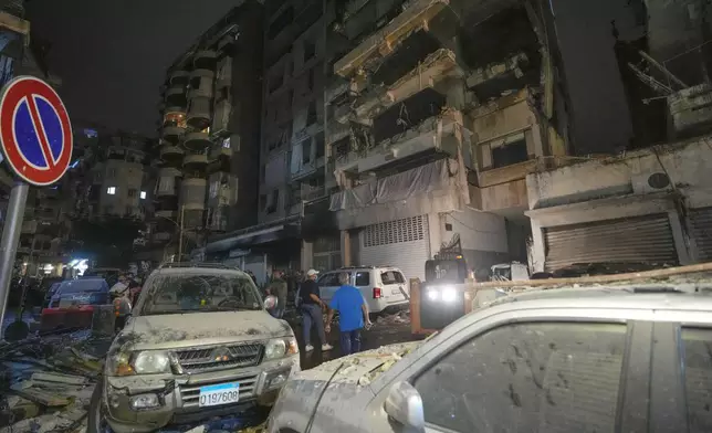 People gather in front of buildings hit by an Israeli airstrike at the site of an Israeli airstrike in Beirut, Lebanon, Thursday, Oct. 10, 2024. (AP Photo/Hassan Ammar)