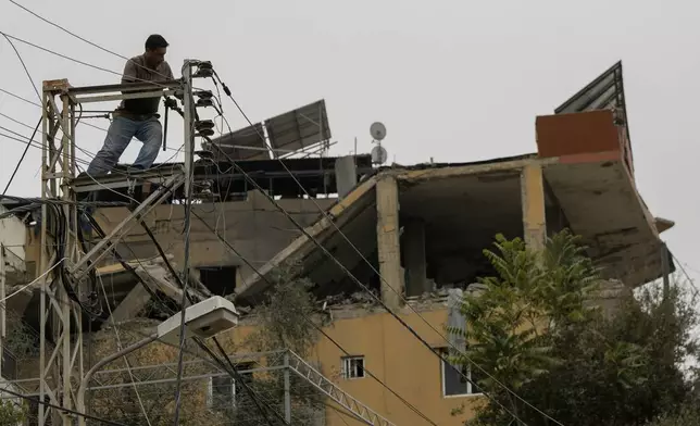 A man fixes power cables in front of a building that was hit by Israeli airstrikes in the village of Qmatiyeh, southeast Beirut, Lebanon, Monday, Oct. 7, 2024. (AP Photo/Bilal Hussein)