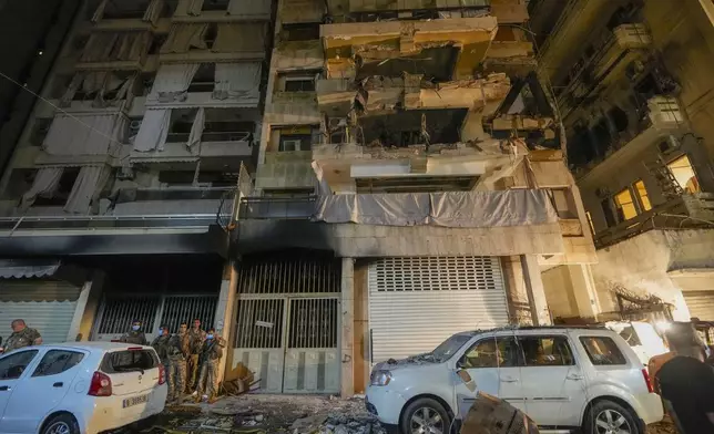 Soldiers stand guard under a building hit by an Israeli airstrike in Beirut, Lebanon, Thursday, Oct. 10, 2024. (AP Photo/Hassan Ammar)