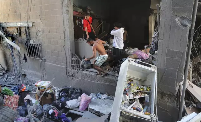 Lebanese citizens collect their belongings from their destroyed apartment that was hit by an Israeli airstrike, in Tyre, south Lebanon, Thursday, Oct. 24, 2024. (AP Photo/Mohammed Zaatari)