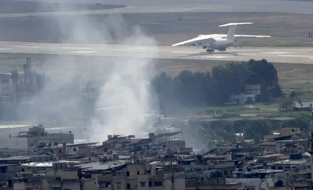 A plane take off from Rafik Hariri international airport as smoke of a past Israeli airstrike still rise from Dahiyeh, in Beirut, Lebanon, Monday, Oct. 14, 2024. (AP Photo/Hussein Malla)