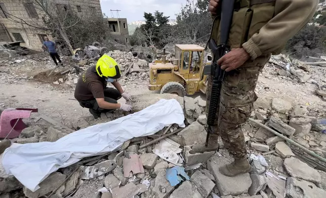 A Civil Defence worker searches for body remains between the rubble of a destroyed building at the site of Monday's Israeli airstrike in Aito village, north Lebanon, Tuesday, Oct. 15, 2024. (AP Photo/Hussein Malla)