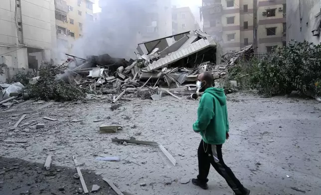 A man passes in front of a destroyed building that hit by an Israeli airstrike in Dahieh, Beirut, Lebanon, Wednesday, Oct. 2, 2024. (AP Photo/Hussein Malla)