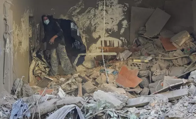 A resident of a building damaged in an Israeli airstrike returns to collect her family's belongings at the site of Thursday's Israeli airstrike in Beirut, Lebanon, Friday, Oct. 11, 2024. (AP Photo/Hassan Ammar)