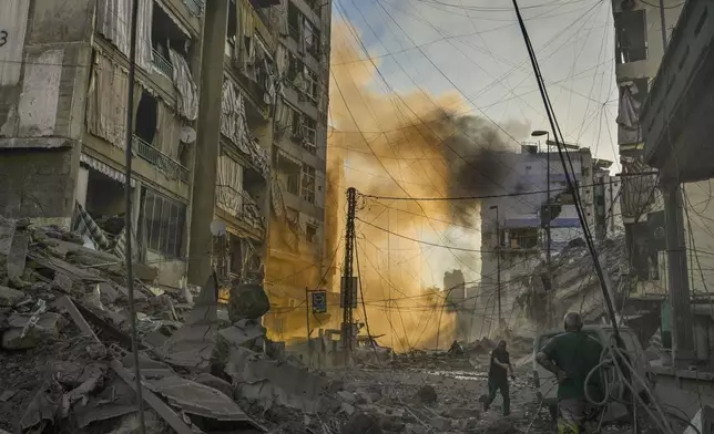 A man runs for cover as a smoke raises in the background following an Israeli airstrike in Dahiyeh, Beirut, Lebanon, Friday, Oct. 4, 2024. (AP Photo/Hassan Ammar)