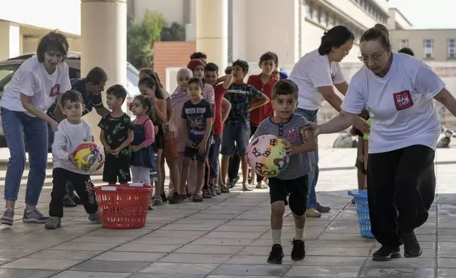 Volunteers of the Russian Cultural Center entertain displaced children at a school in Beirut, Lebanon, Thursday, Oct. 3, 2024, after fleeing the Israeli airstrikes in the south. (AP Photo/Bilal Hussein)